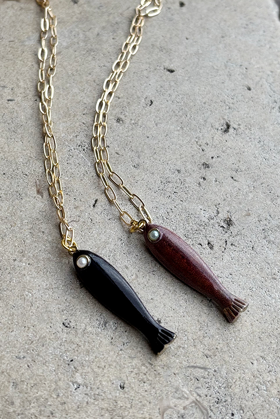Necklace with black and brown fish pendants on a concrete surface
