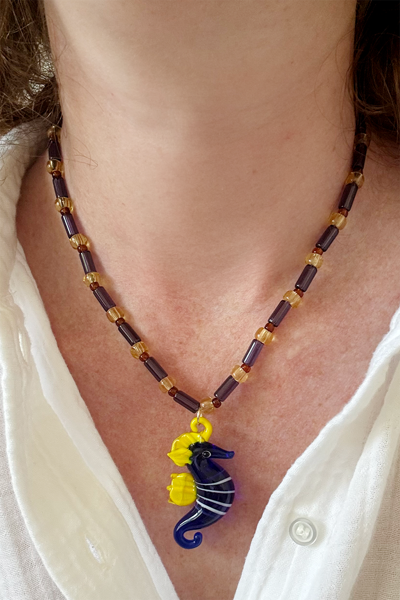 Necklace with a blue seahorse pendant worn by a person