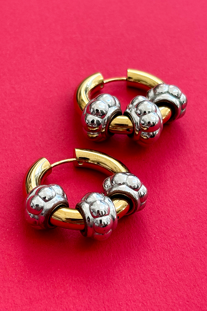 Gold and silver hoop earrings on a red background