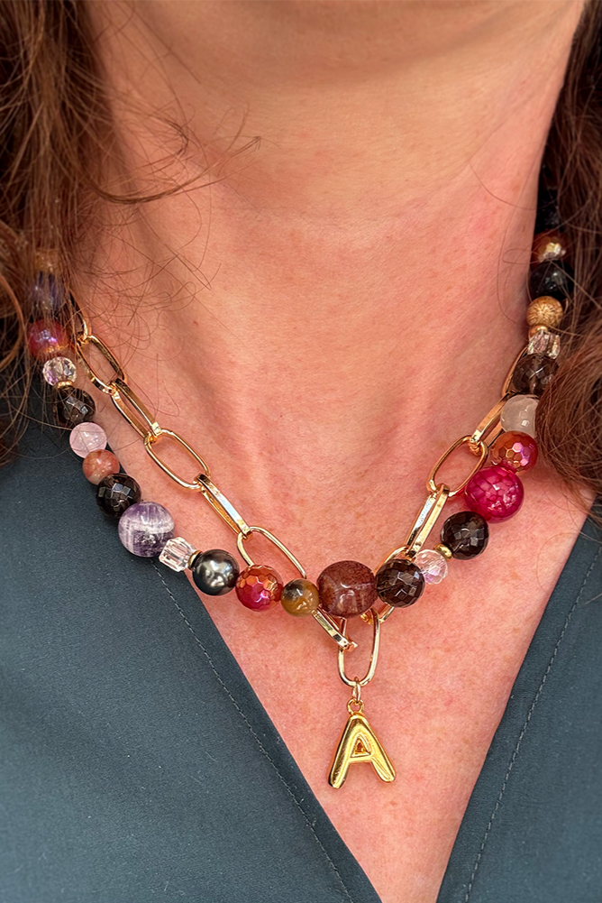 Necklace with multicolored beads and a gold chain, worn by a person.