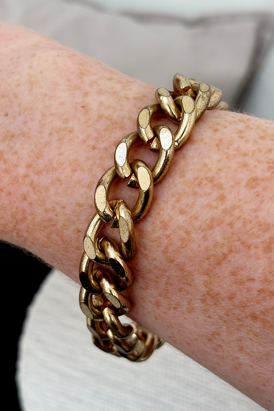 Gold chain bracelet on a wrist with a blurred background