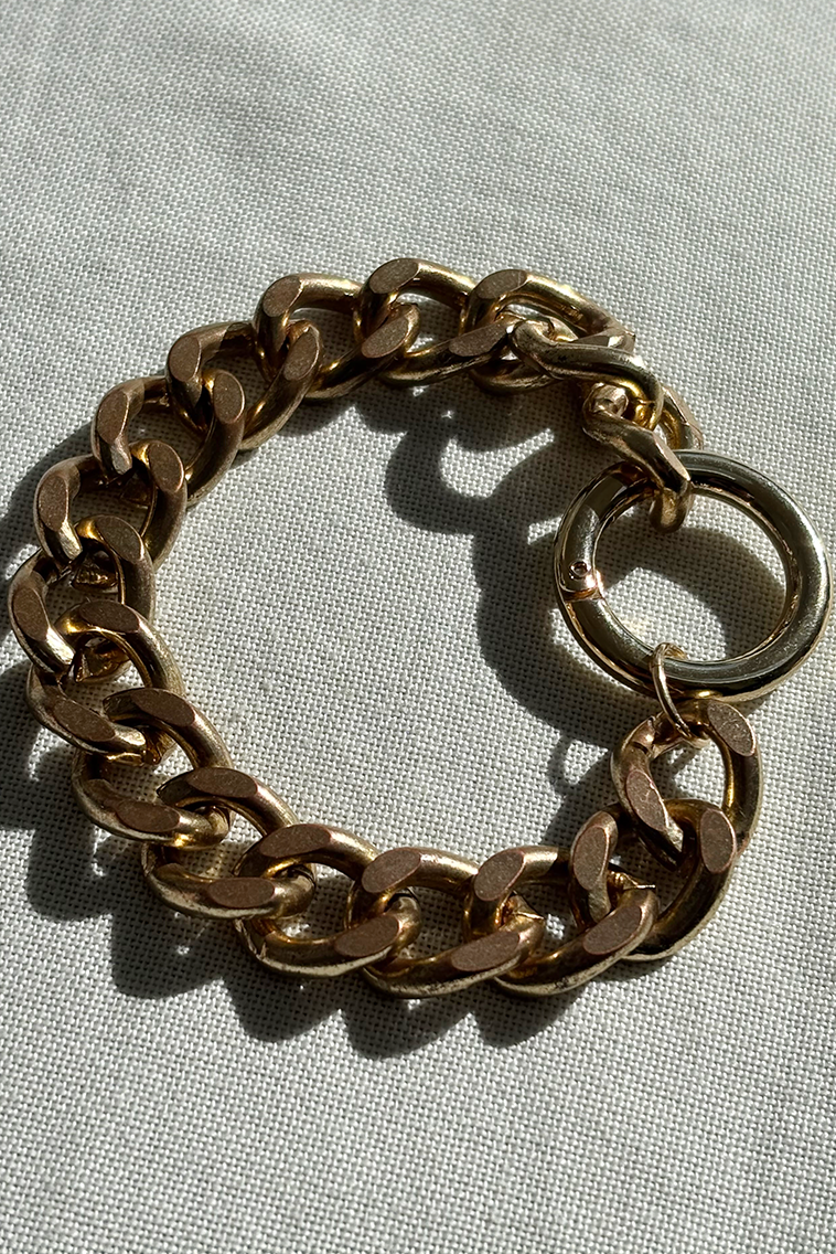 Gold chain bracelet on a light gray background