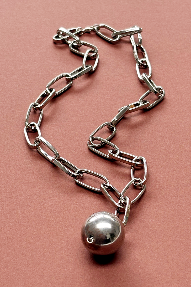 Silver chain with a spherical pendant on a pink background