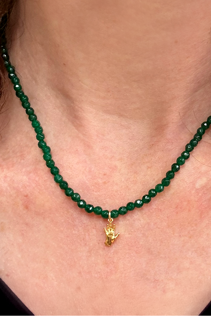 Green beaded necklace with a gold pendant worn by a person