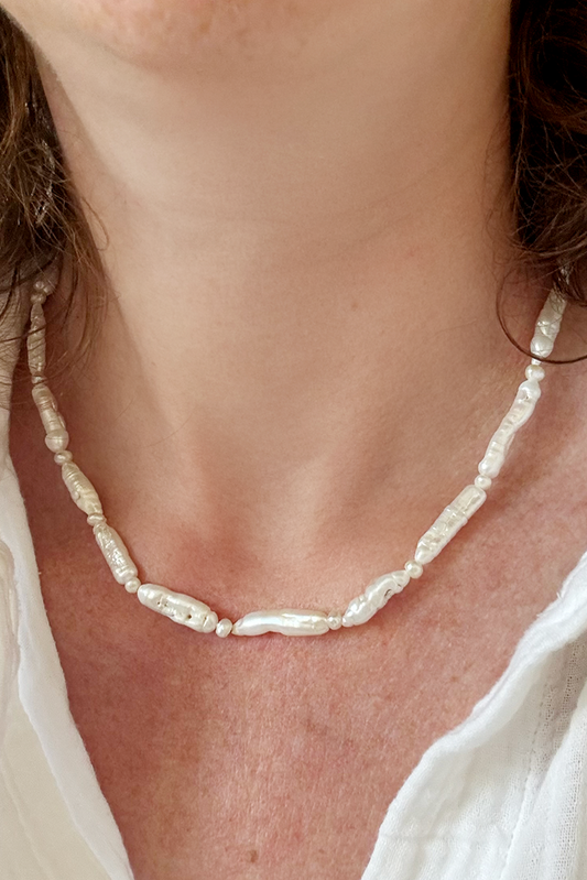 Pearl necklace worn by a person with a white shirt